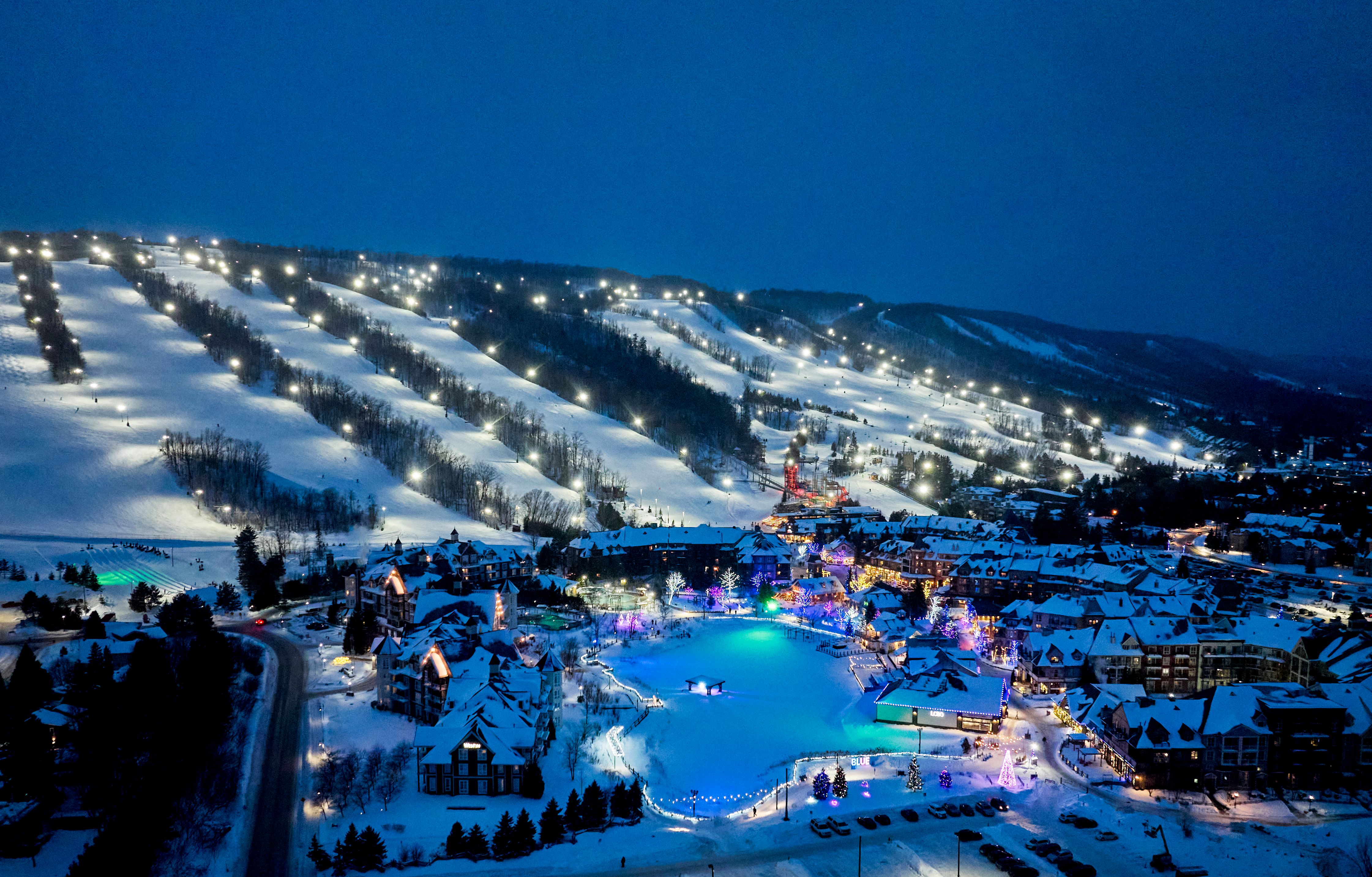 A nighttime aerial view of Blue Mountain and Village, showcasing the lit up slopes and Holiday Magic Light Trail.