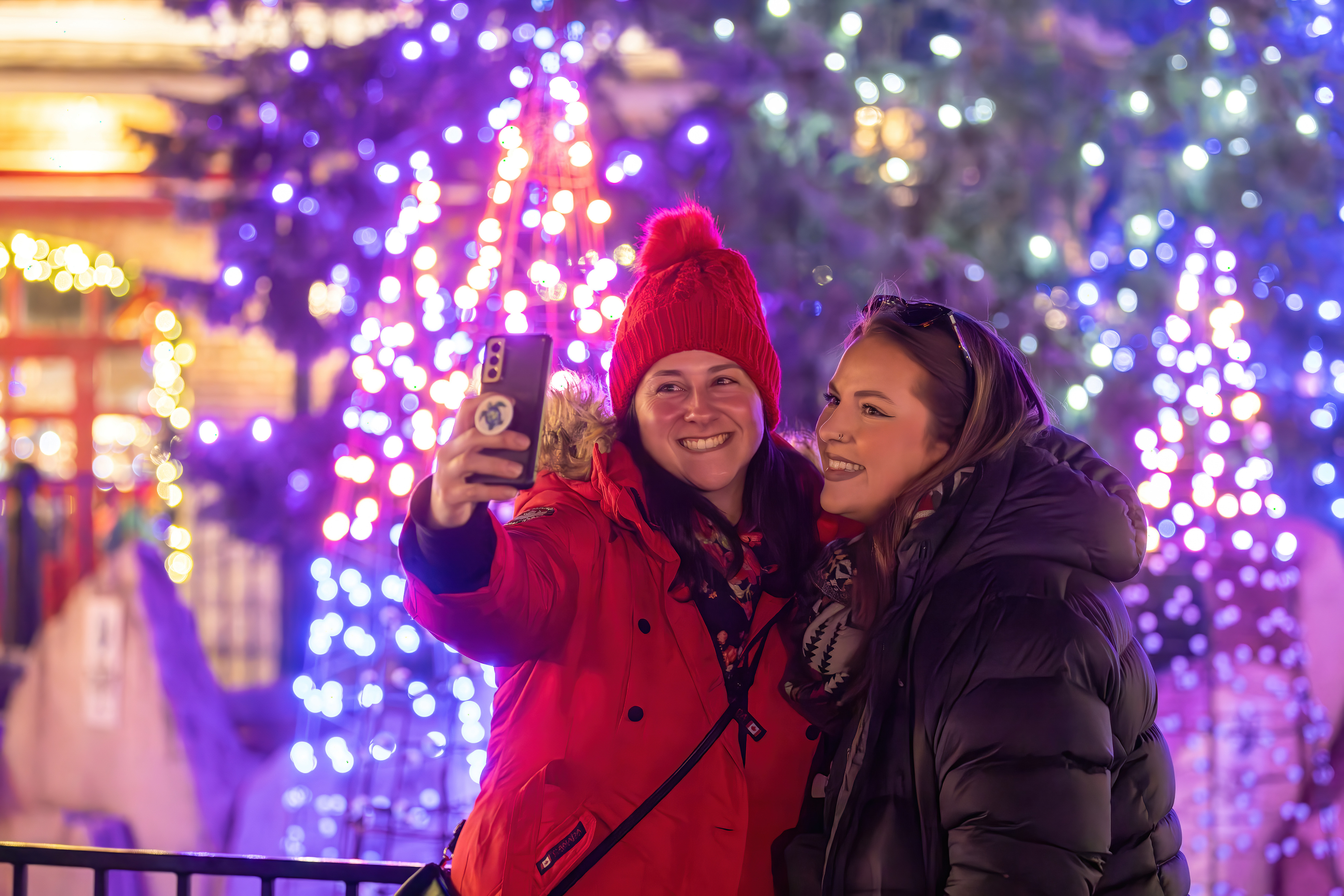 Two besties taking a winter selfie against the backdrop of the Holiday Magic Light Trail