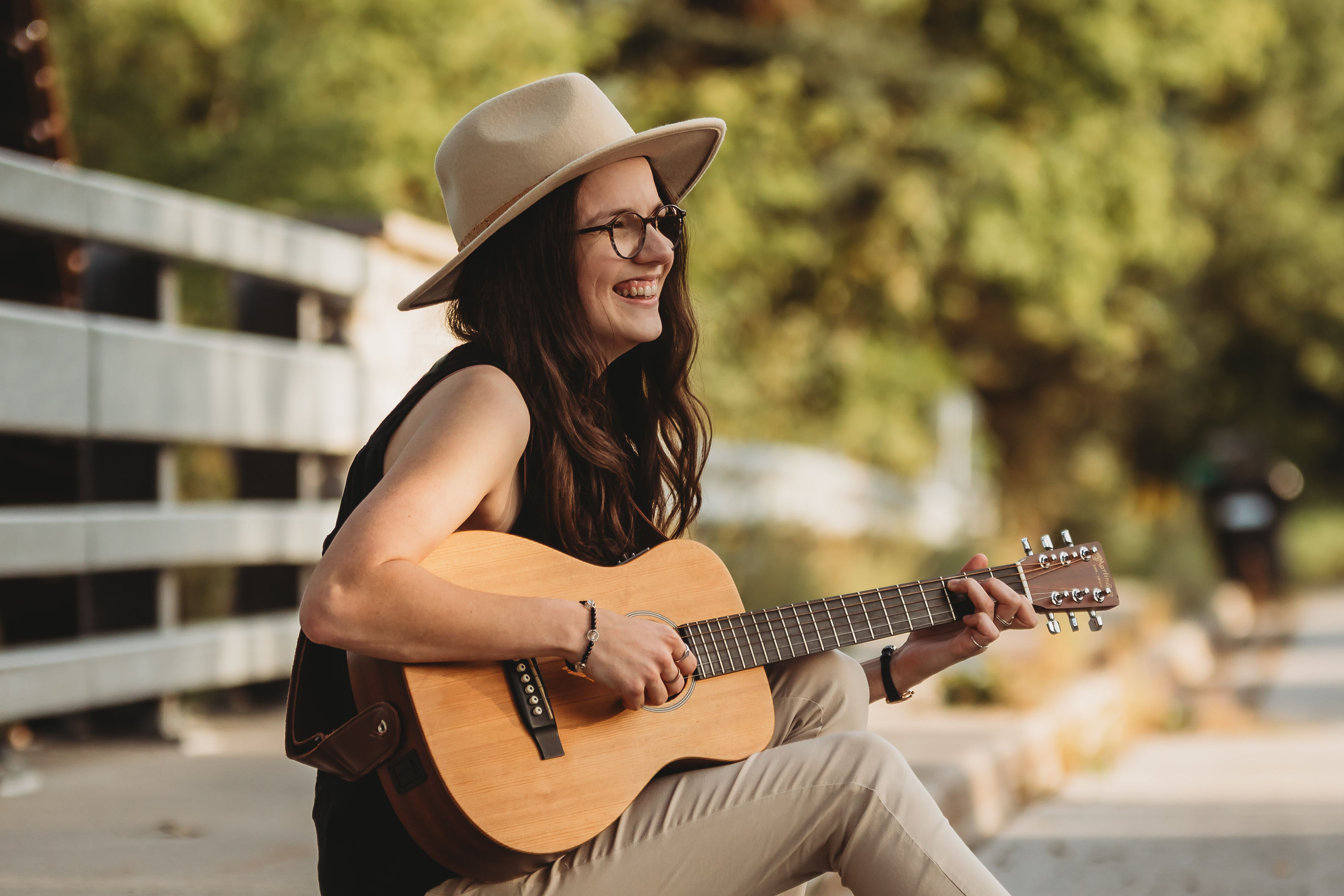 Side profile shot of singer, Jess Bowman, smiling and playing her acoustic guitar