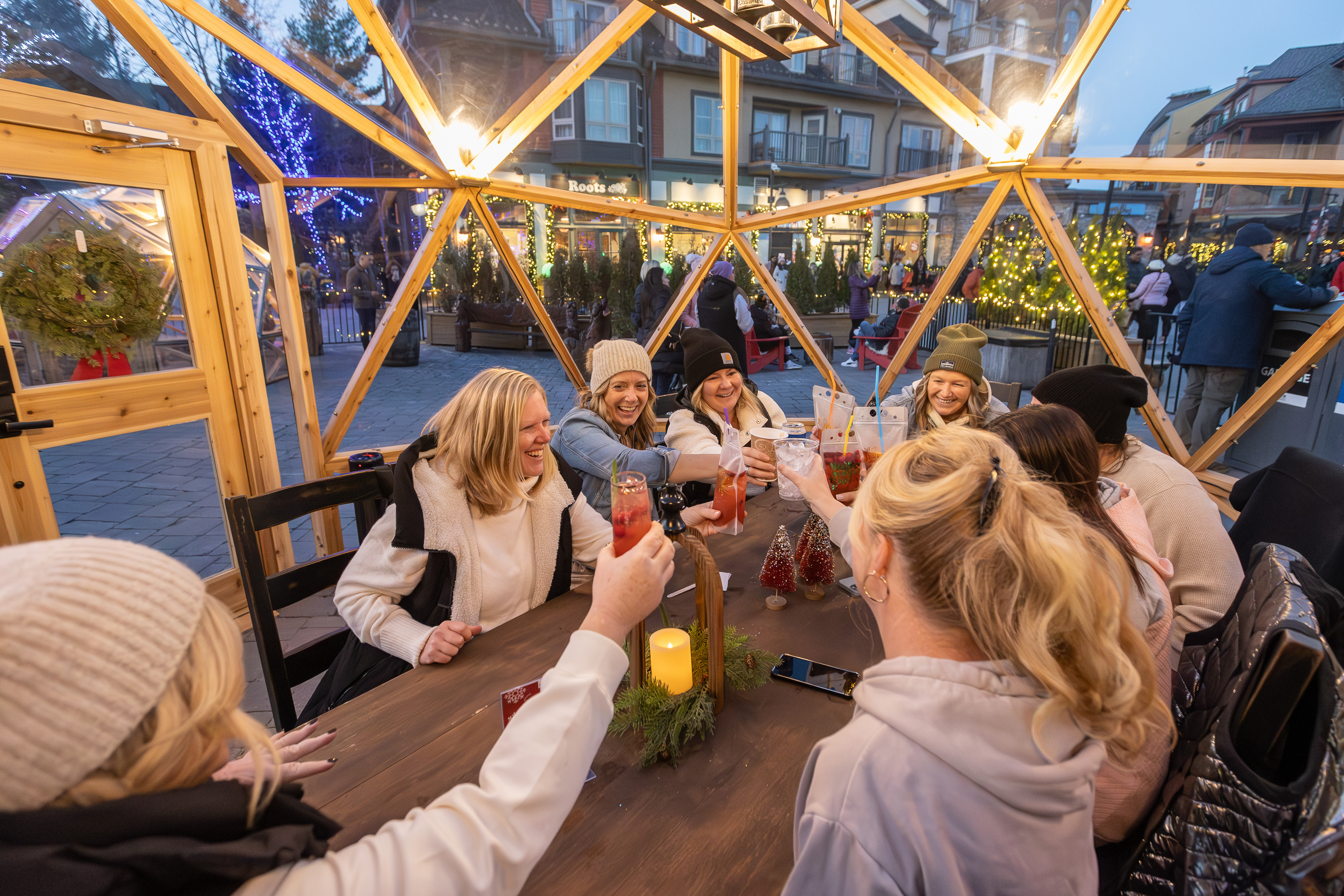 Large friend group cheersing their festive cocktails together inside a lit Snowdome.