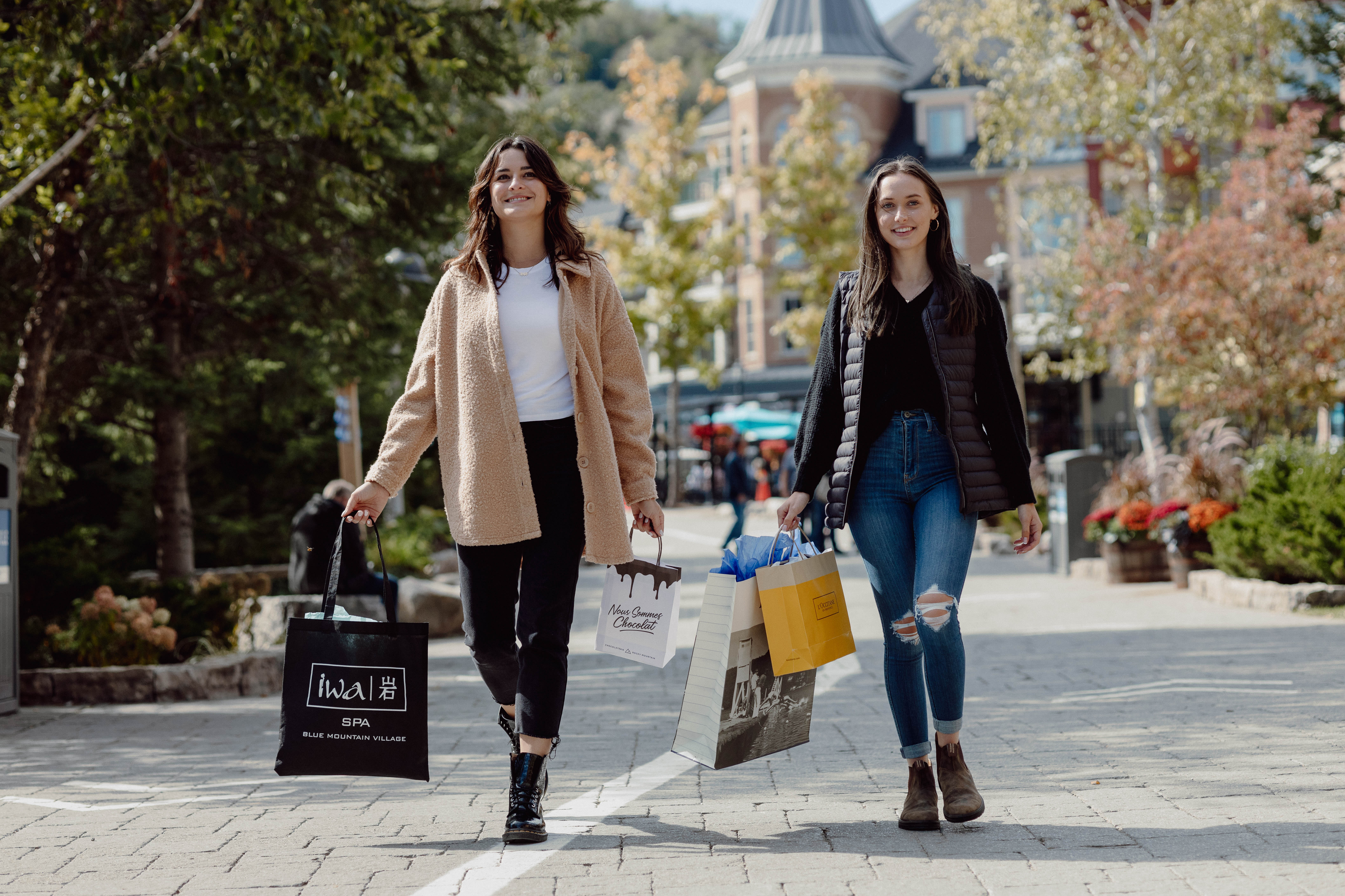 Two friends walking through the village with shopping bags on a sunny day. 