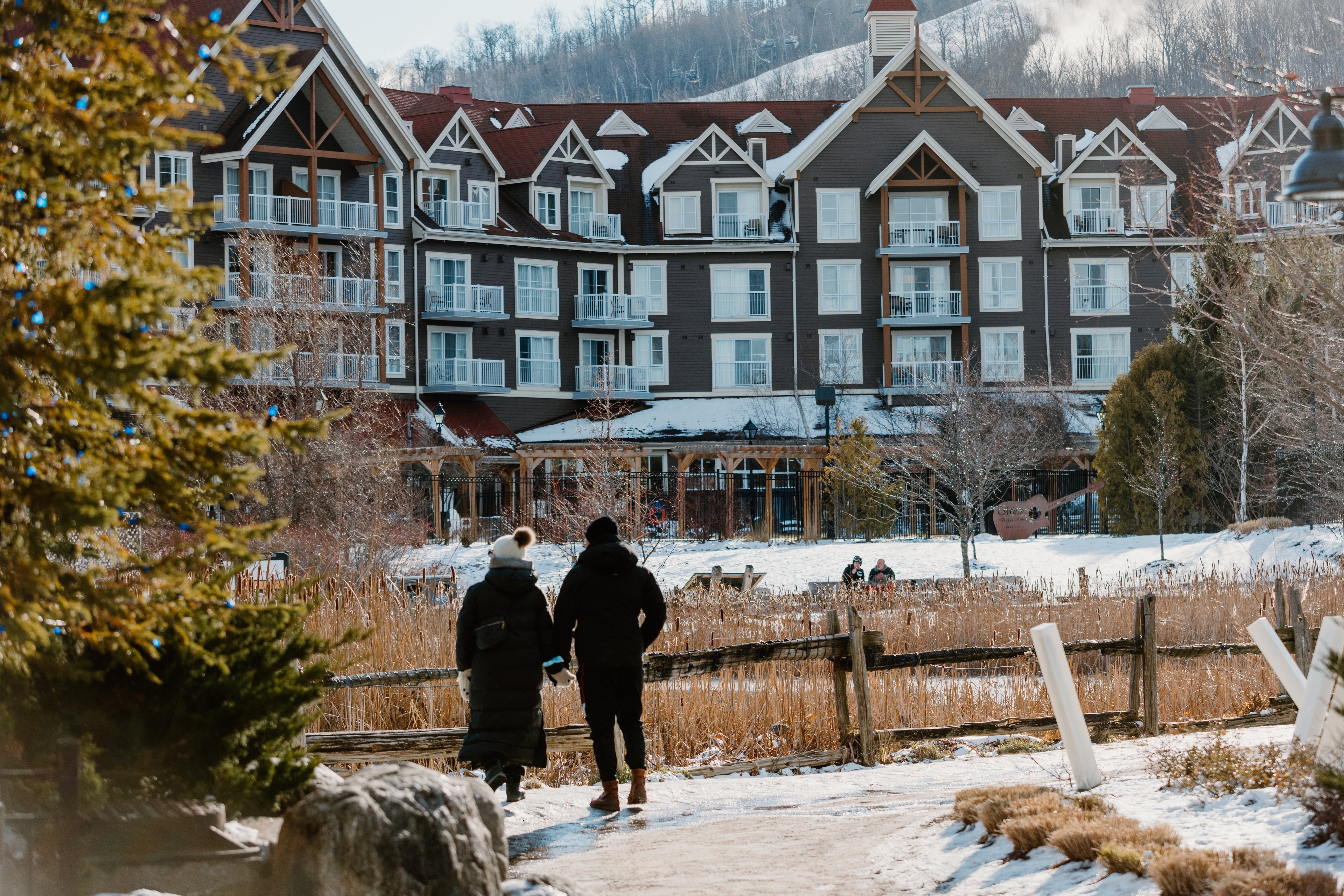 A couple strolls the village in winter with the Westin Trillium displayed in the background. 