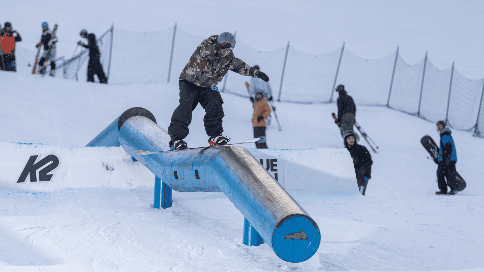 Snowboarder doing a front-side 50/50 over a triple kink during Frozen Rail Jam at Blue Mountain Resort.