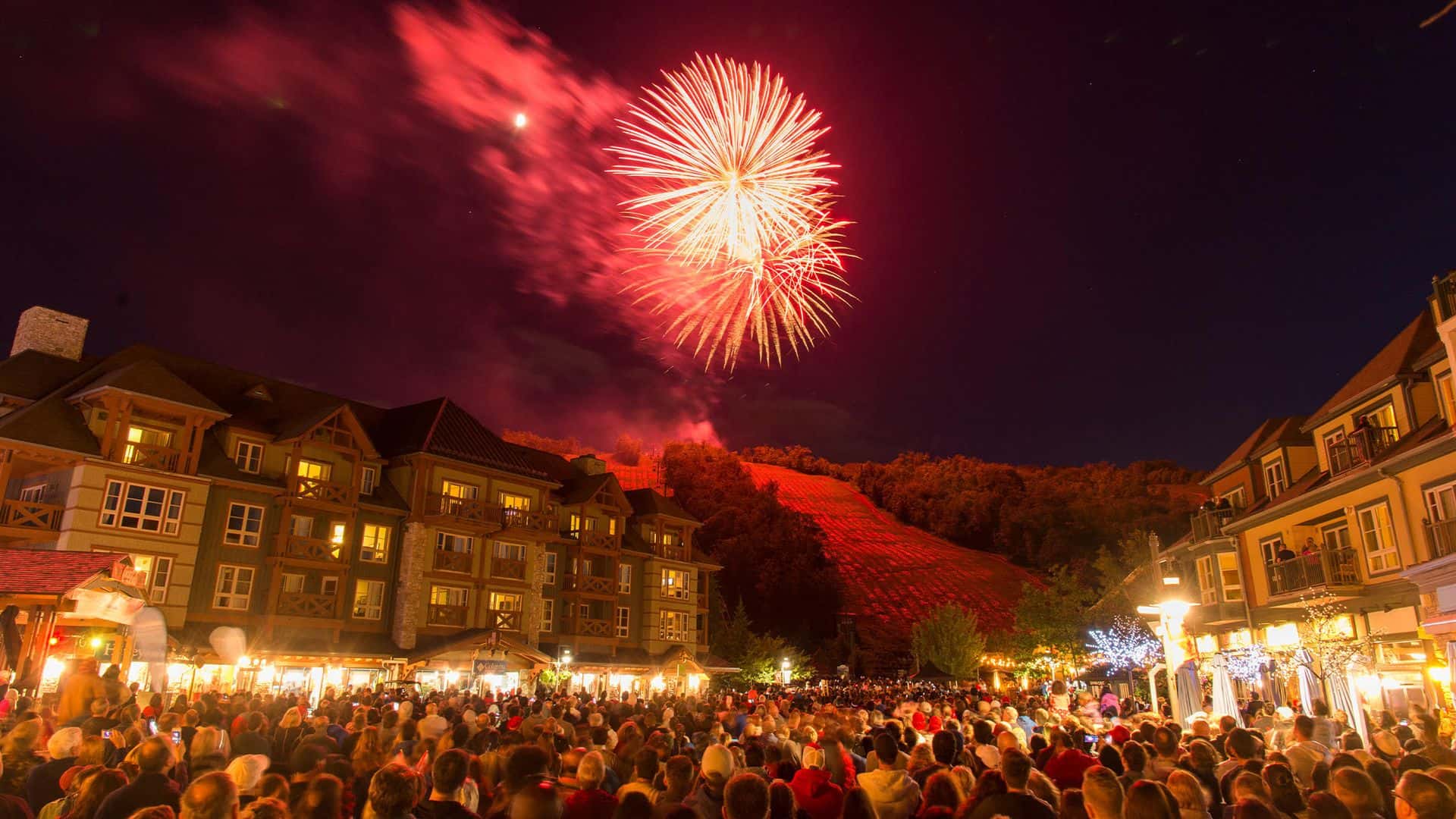 Fireworks bursting over crowds of people in the Village Events Plaza in celebration of Canada Day at Blue.