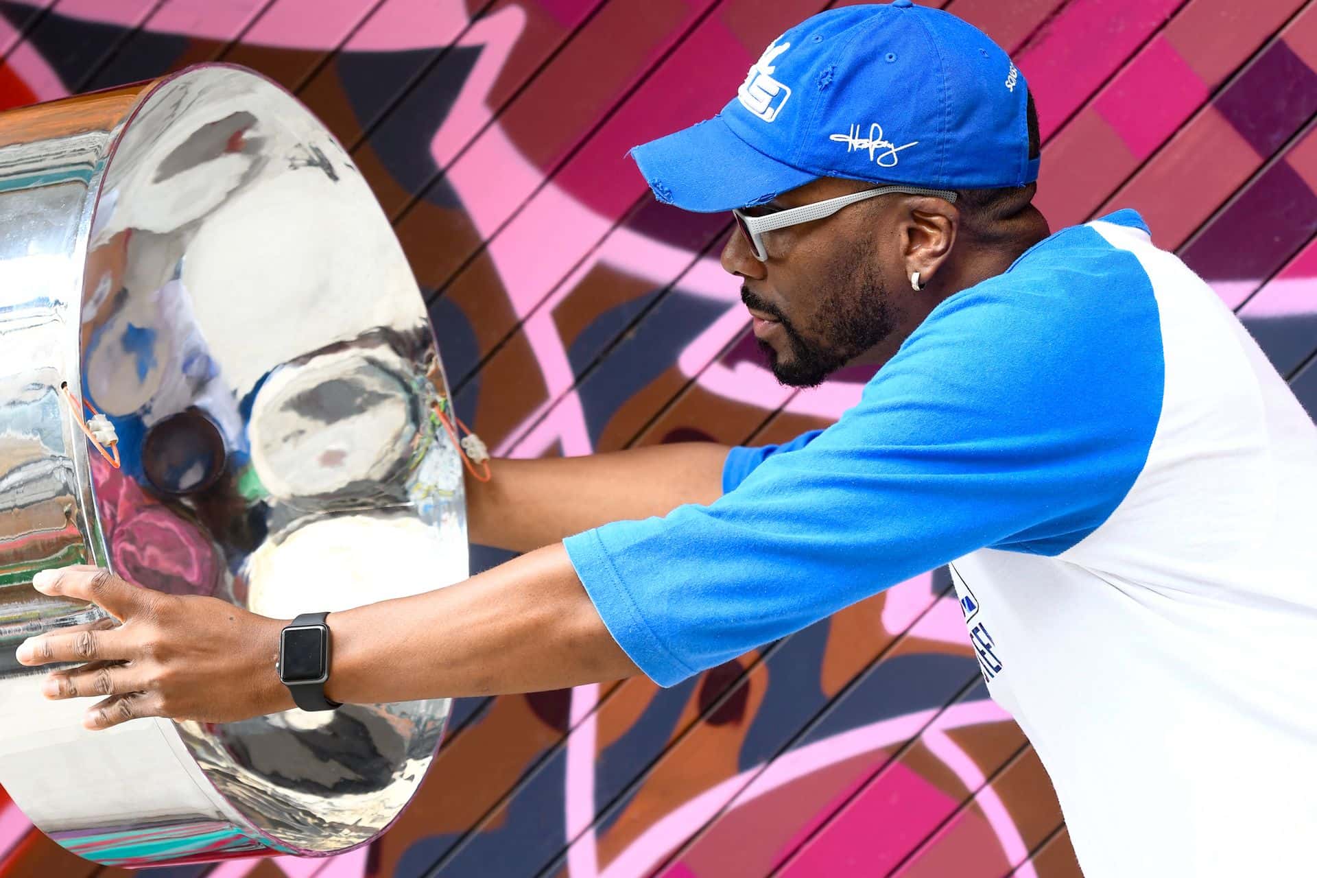 Photo of Caribbean Winterfest performer, Earl La Pierre Jr. (aka E-man), holding up a steel pan and looking into it like a mirror.