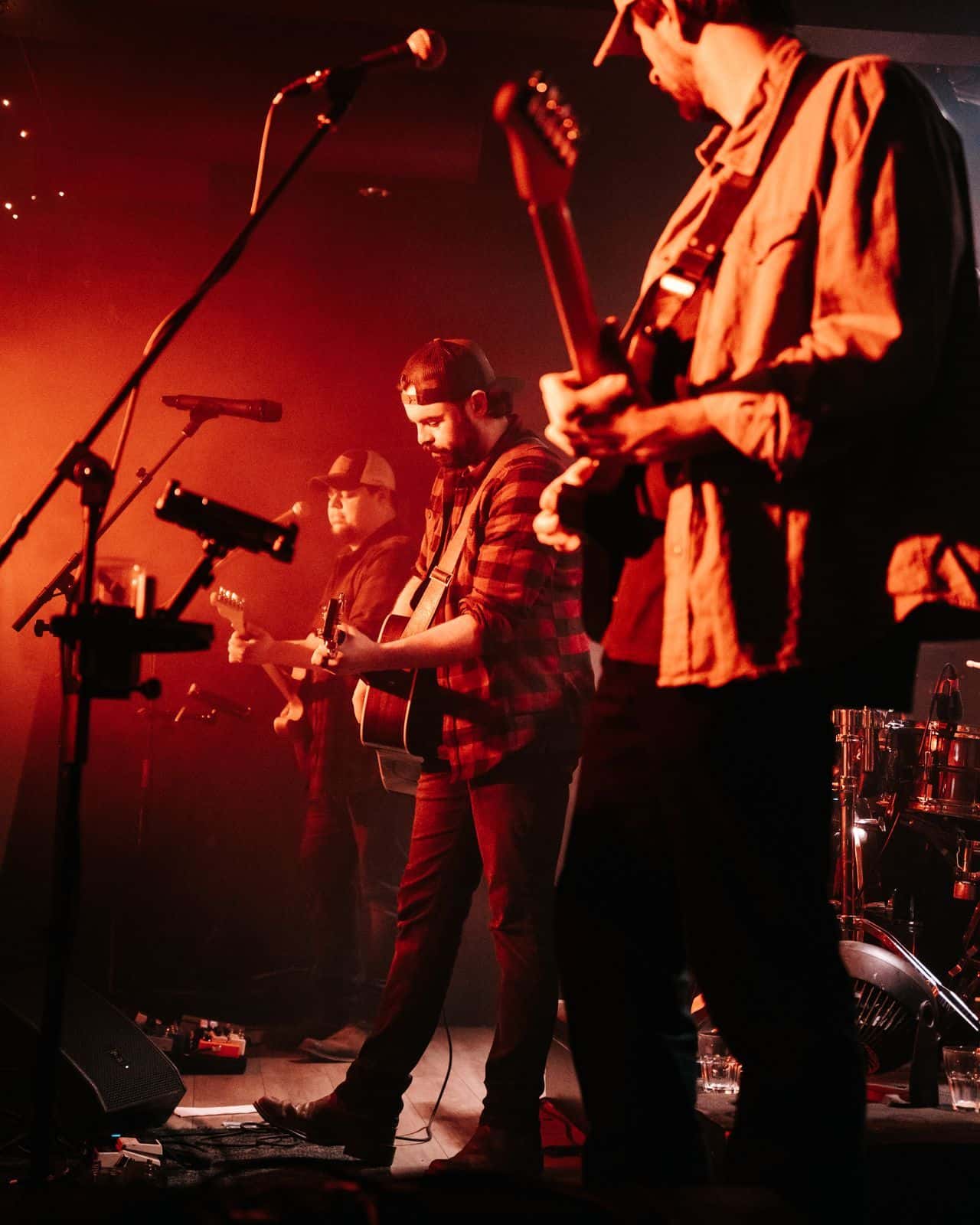 Dean James Band performing live beneath red and orange stage lights