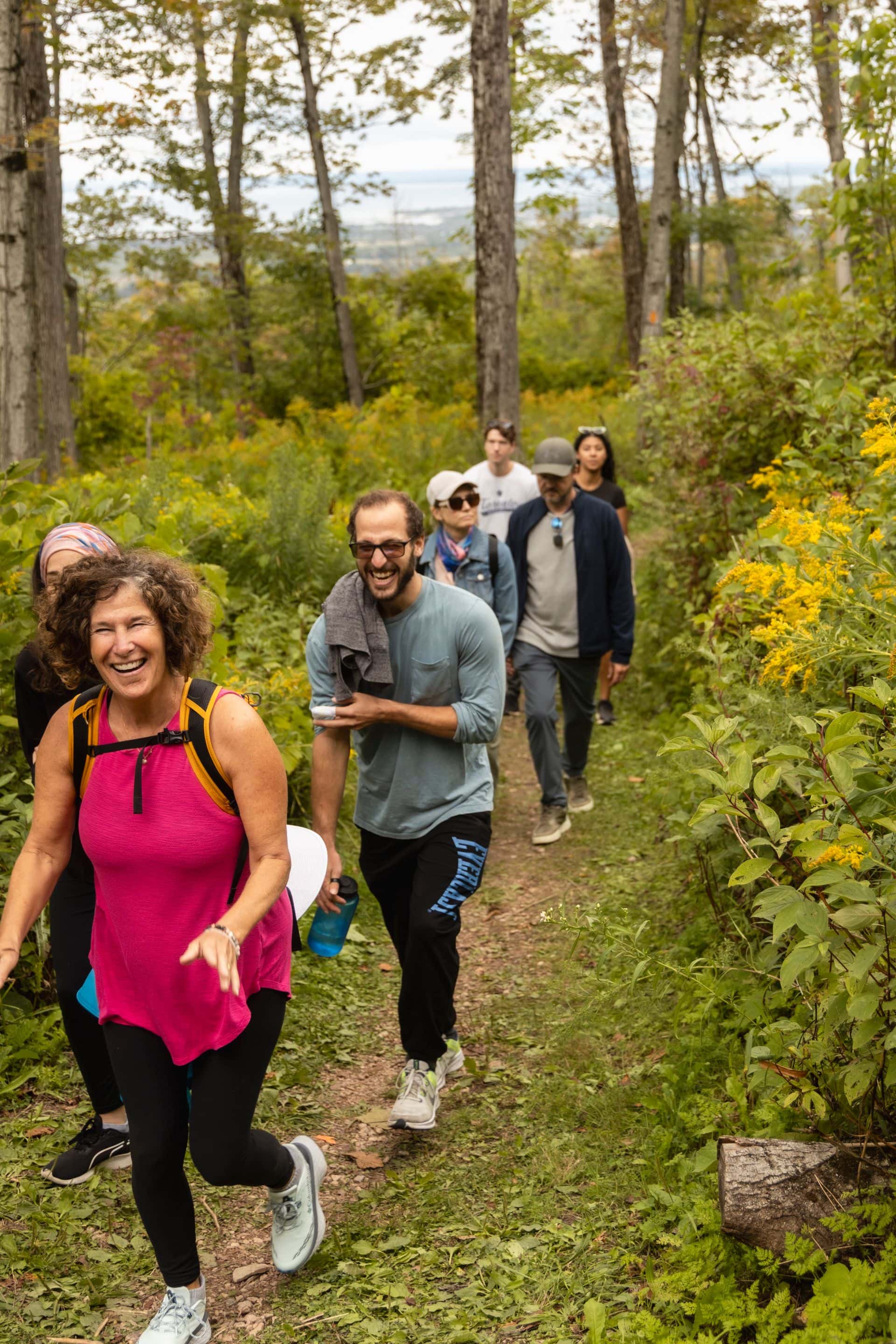 A group of hikers ascending up the mountain with big smiles as they discover musical performers along the Guitar Trail.