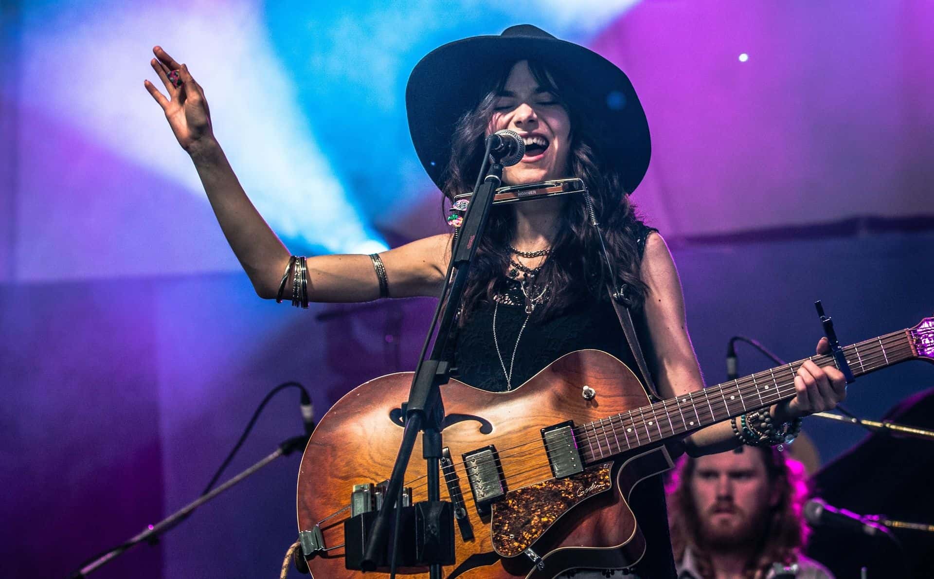 Ontario musician, Madison Galloway, performing live on stage. singing with her electric guitar and harmonica.