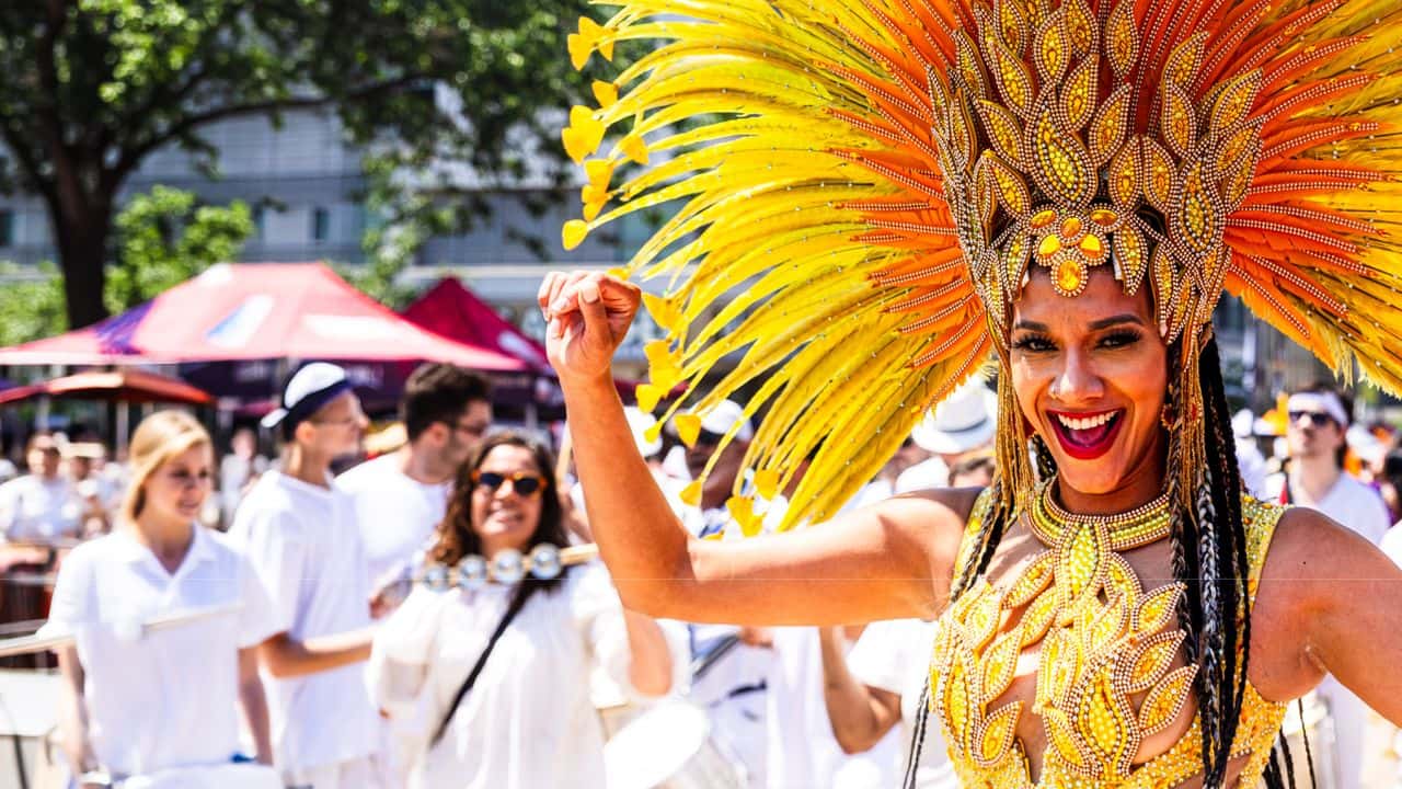 A beautiful latina dancer dressed in traditional Brazilian feathers and headdress performing live