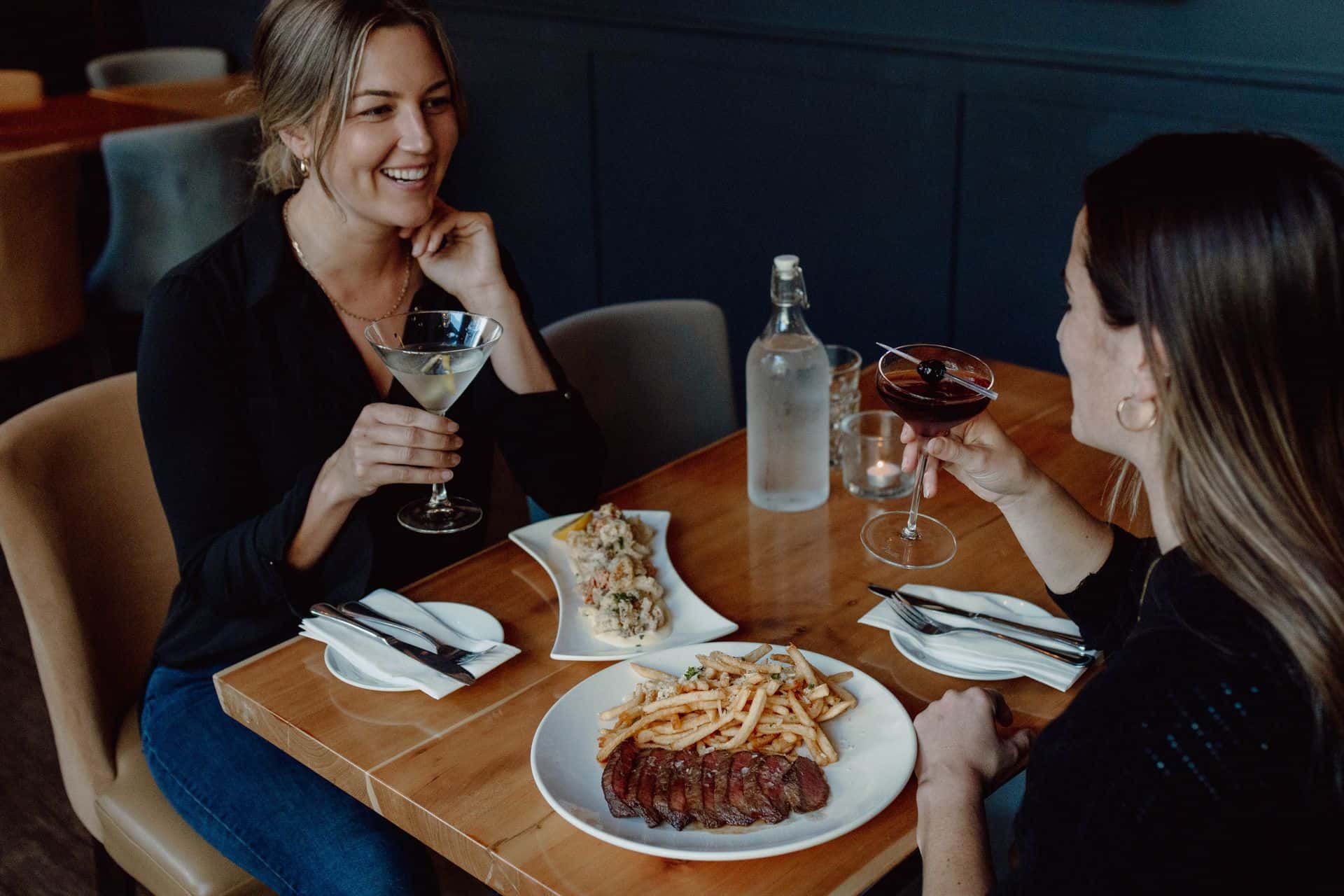 Two friends enjoy dinner with drinks at Twist Kitchen + Cocktail. 