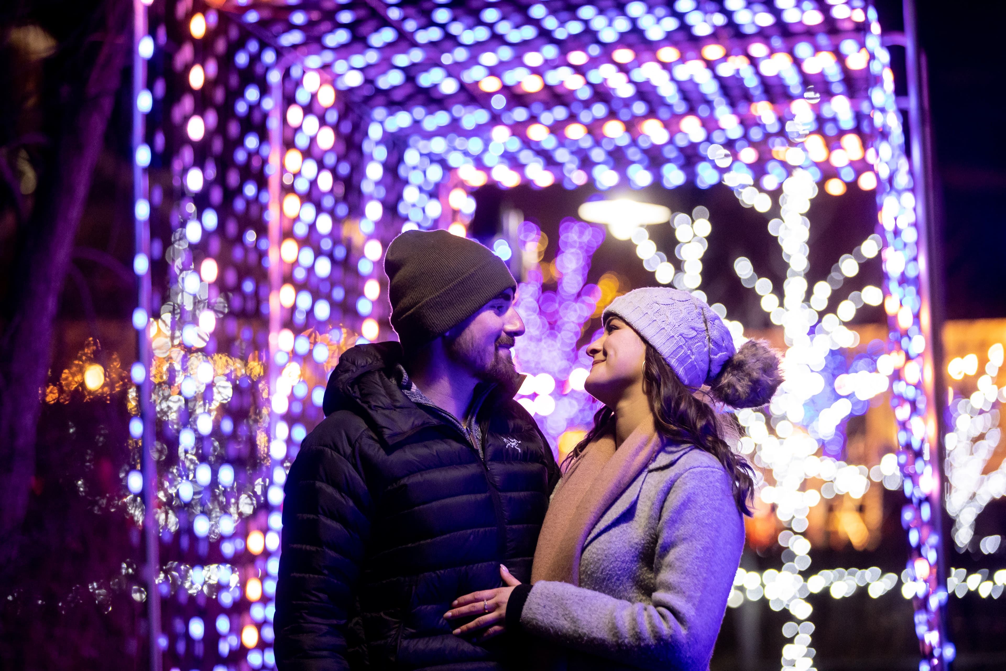 Couple embracing each other beneath the glowing lights of the Holiday Magic Light Trail at Blue Mountain Village