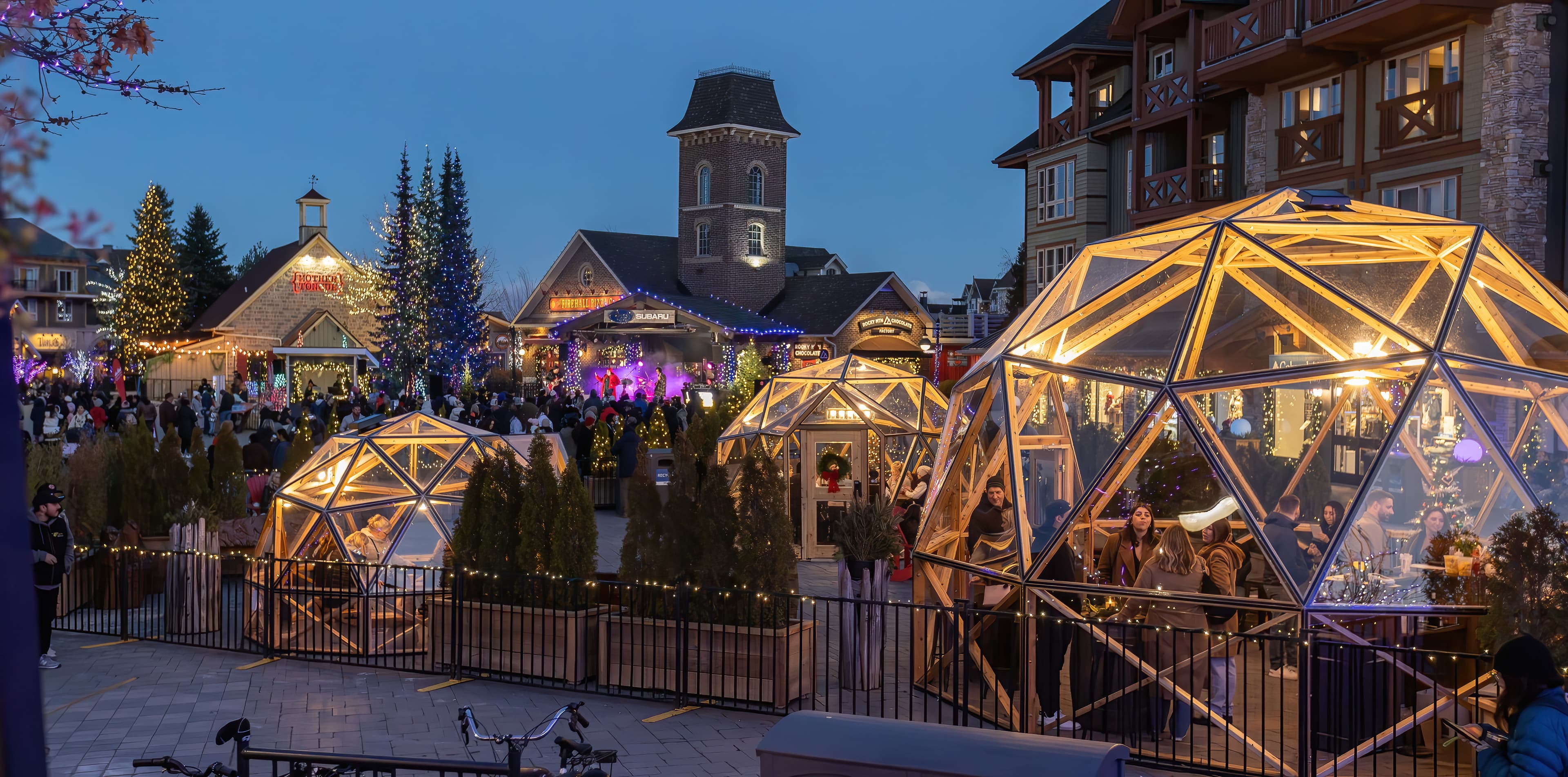 An exterior shot of the Snowdome Cocktail Garden glowing in the Village Events Plaza for Holiday Magic