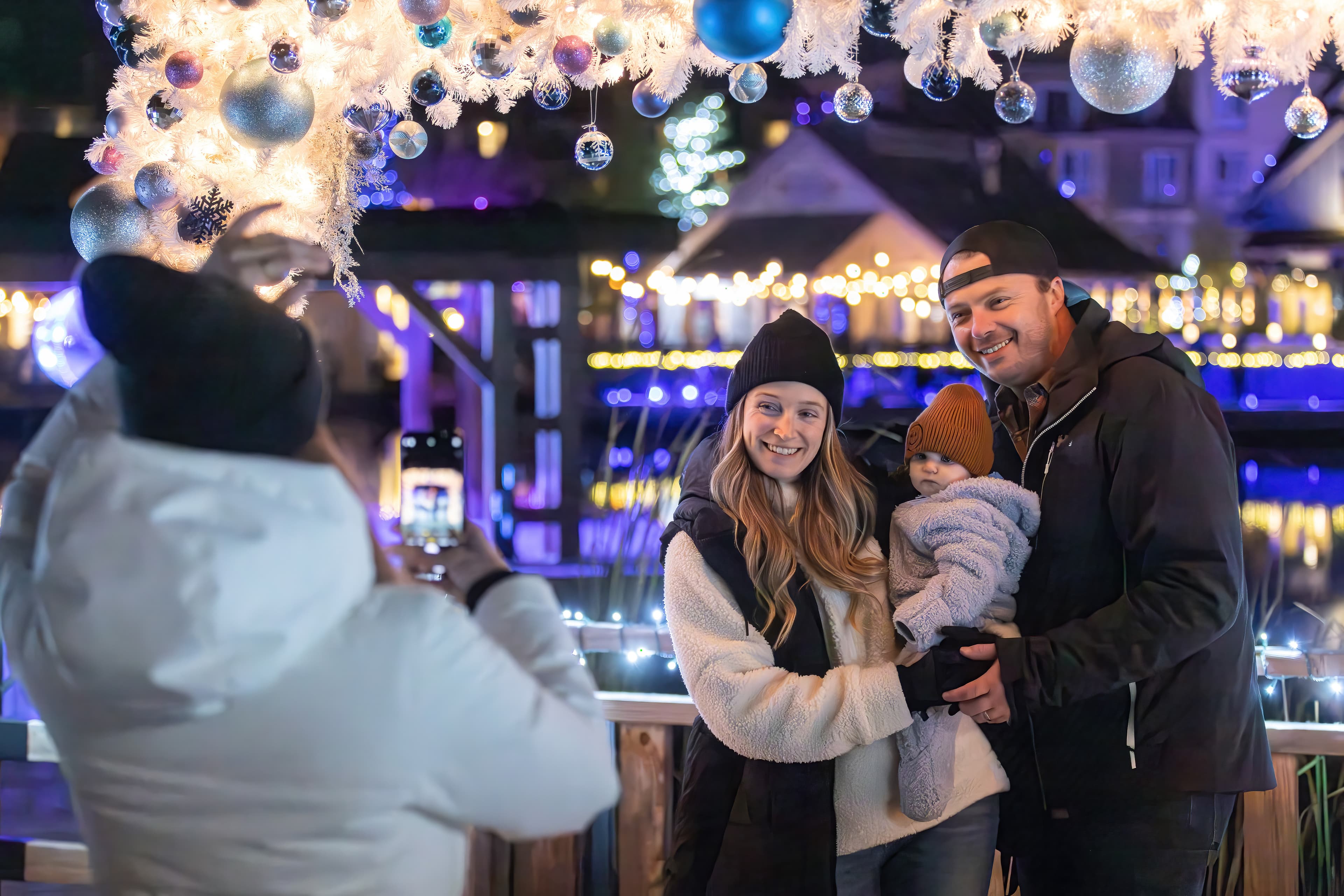 Family of three having their photo taken in the festively adorned photo frame along the Holiday Magic Light Trail