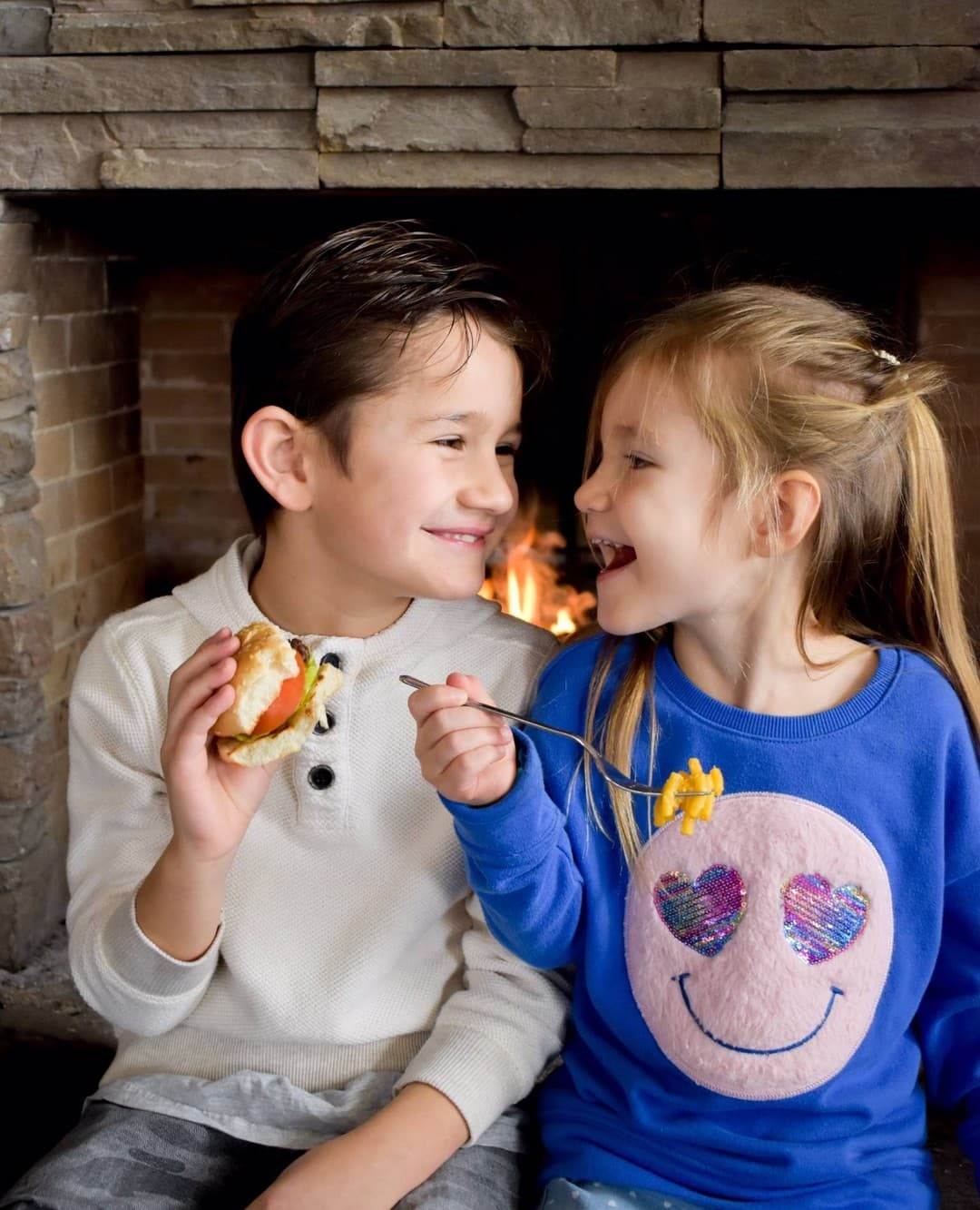 Two kids enjoying dinner at Kaytoo, sitting by the fireplace.