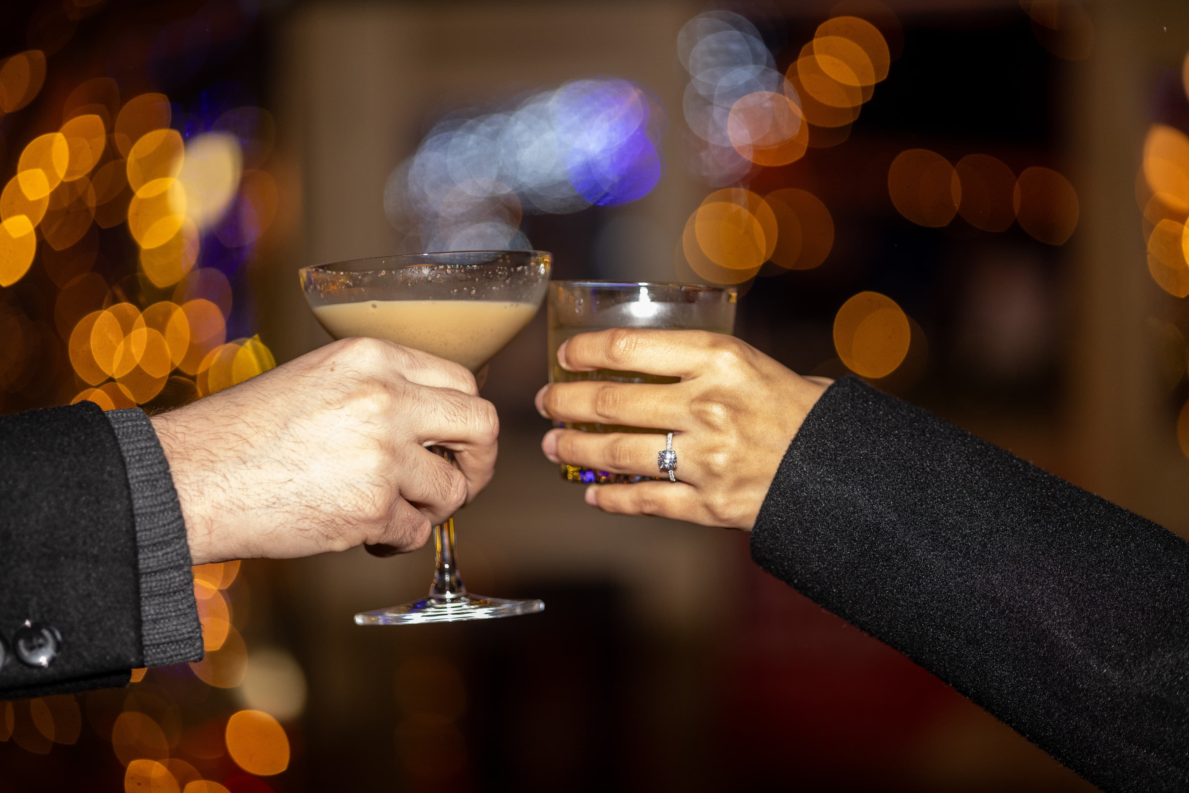 Closeup shot of couple cheersing together festive drinkss in the Snowdome Cocktail Garden.