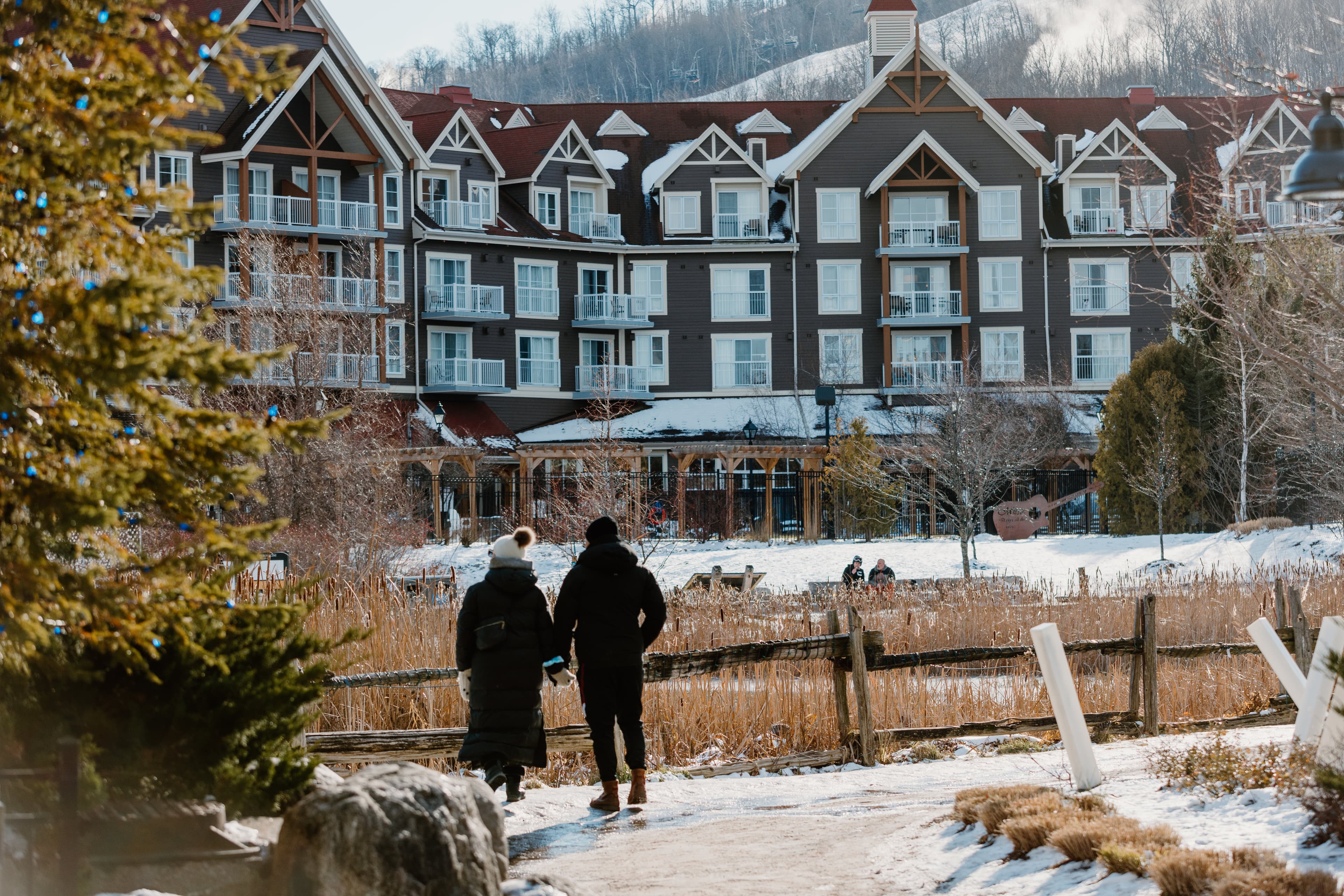 A couple strolls the village in winter with the Westin Trillium displayed in the background. 