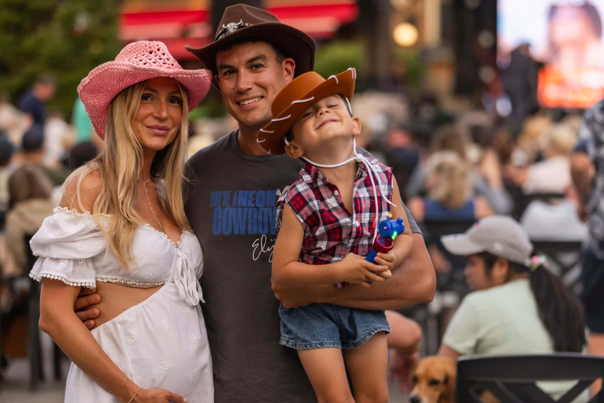 Mom, dad, and their toddler are dressed in full country gear for Gone Country Music Festival in the Village.