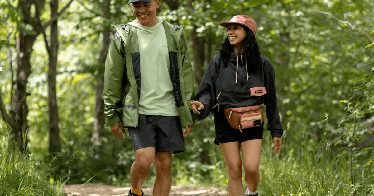 A couple walking hand in hand below a canopy of amber-leaved trees on an hike up the Blue Mountain Resort Explore Park.