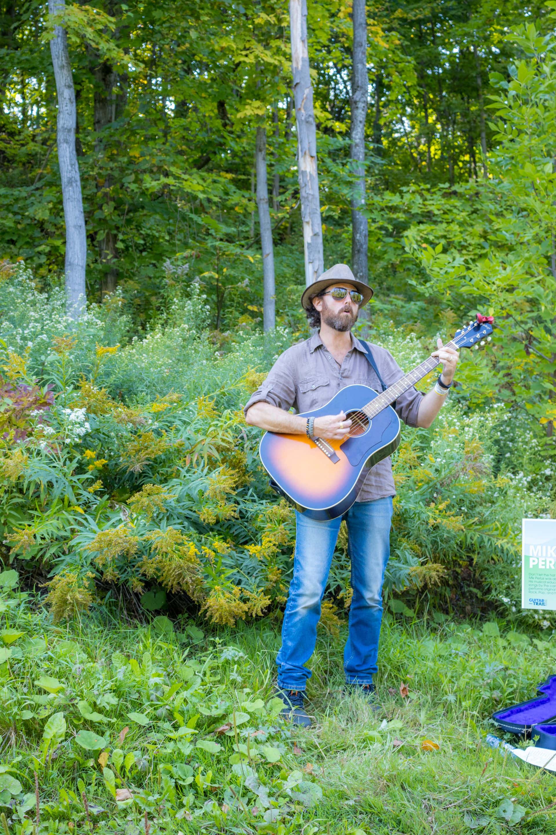 Photo of local musician, Mik Perlus, performing along the Village Way during Guitar Trail 2024.