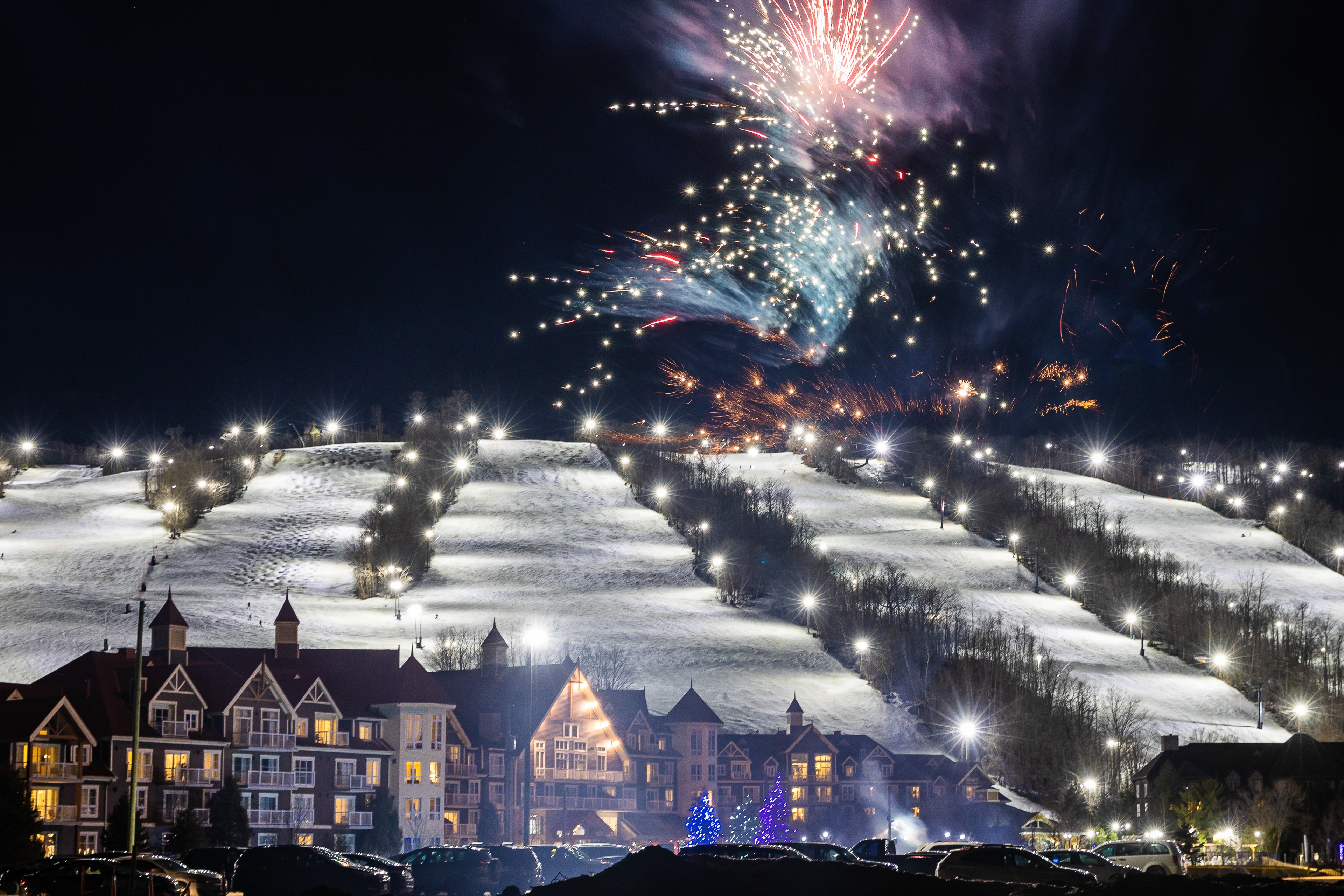Fireworks bursting over the lit up Village and snow covered Mountain for New Years Eve at Blue.