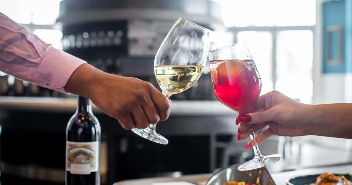 Couple cheersing wine glasses over a table full of beautifully prepared dishes at Oliver & Bonacini Café Grill, located in the Westin Trillium House.