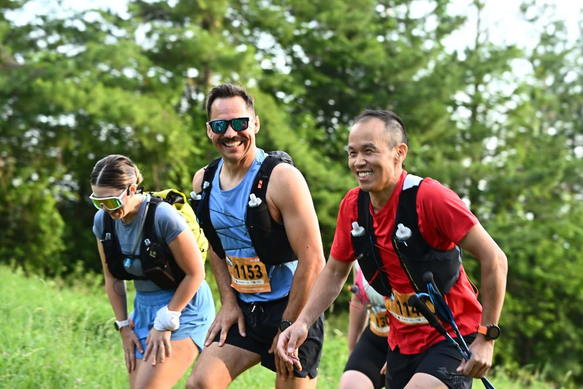 Three atheletes smiling for the camera as they work to race to the top of the Mountain,