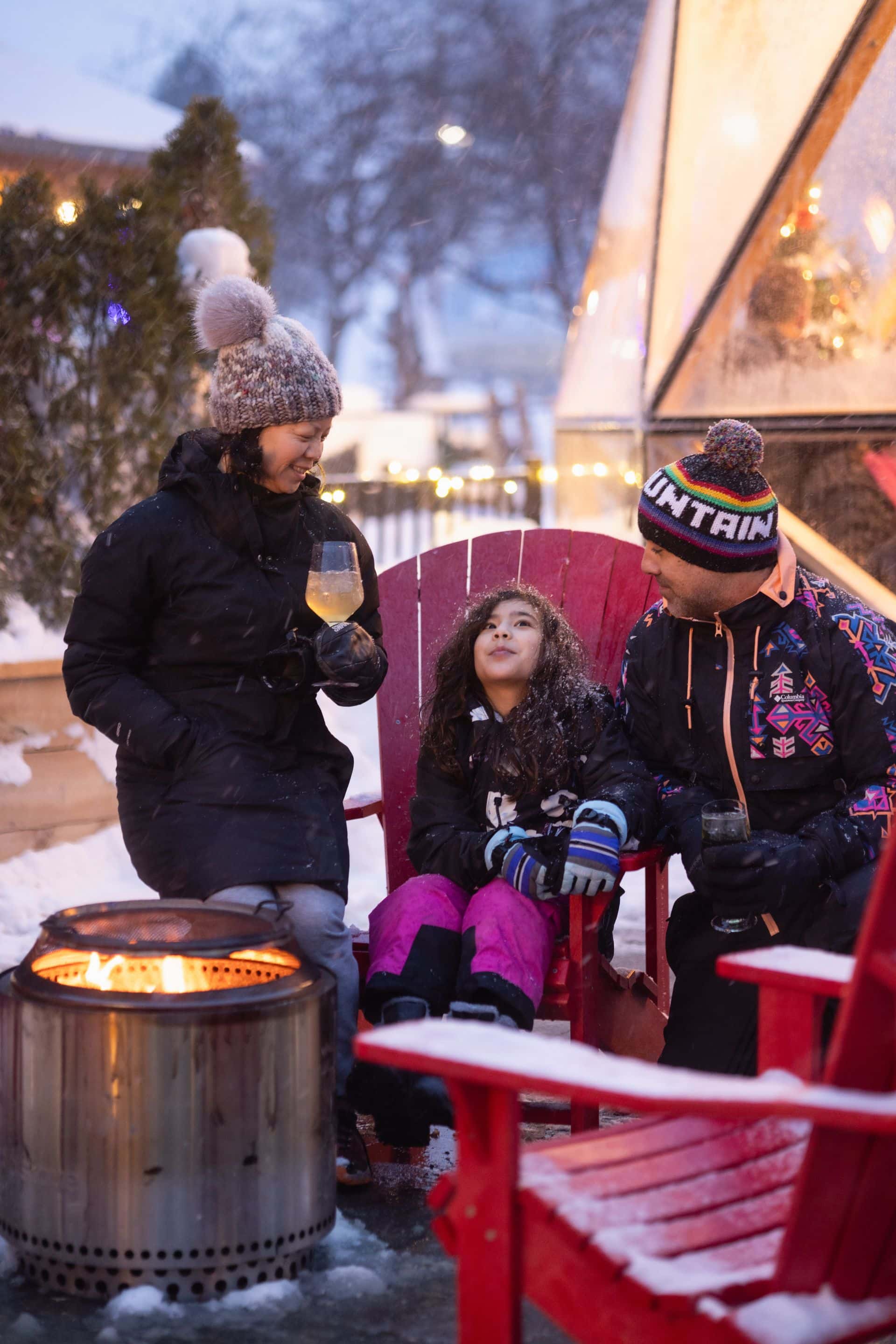 Parents sip cocktails while their daughter enjoys the festive ambience of the Snowdome Cocktail Garden during Holiday Magic.