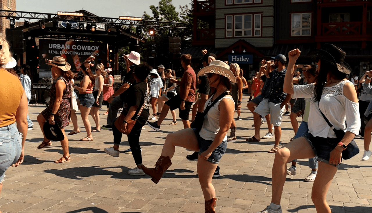 A full plaza of people dressed in their Southern best for Urban Cowboy Line Dancing lessons at Blue Mountain Village