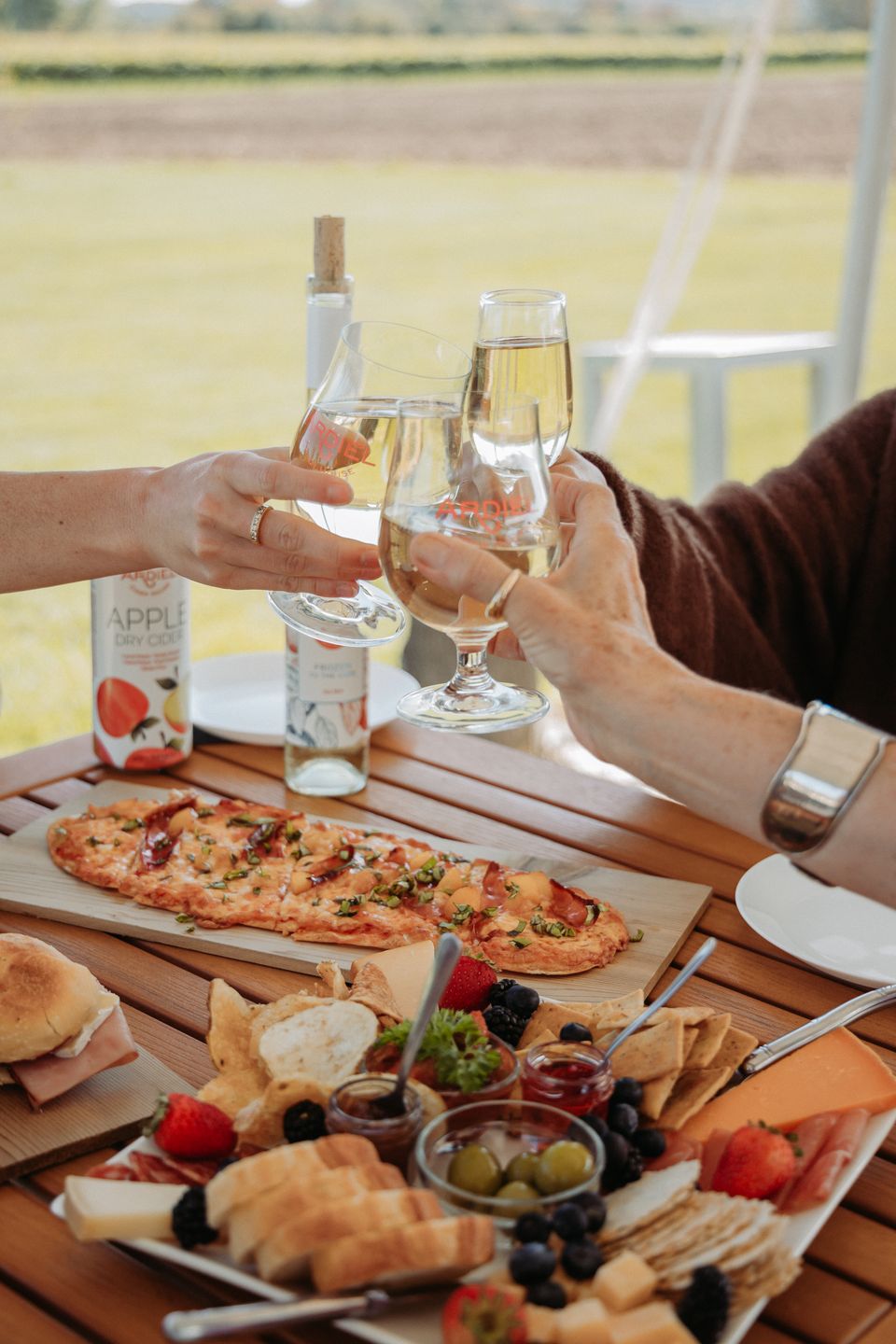 Friends clink together their glasses of local wines and ciders at Georgian Hills Vineyards & Ardiel Cider House, part of the Apple Pie Trail in the Blue Mountains.