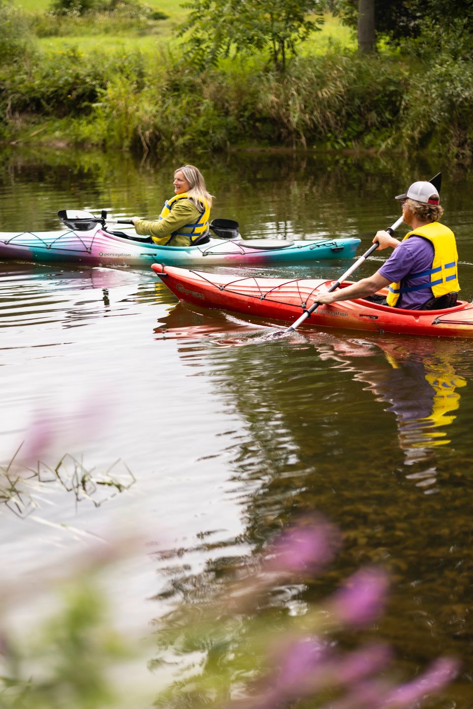 Two friends paddling down the Beaver River with Free Spirit Tours Kayaking on a warm evening.