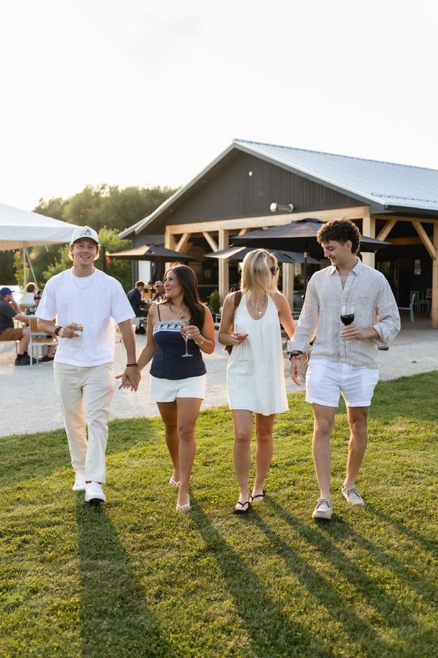 Two couples walking across the outdoor patio/lounge with wine in hand during sunset at Georgian Hills Vineyards.