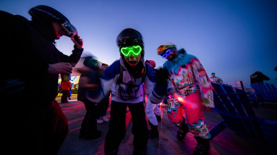 Partiers at the Coors Light College & University Glow Party at Off-Piste, wearing retro 90's ski wear and glowing glasses.