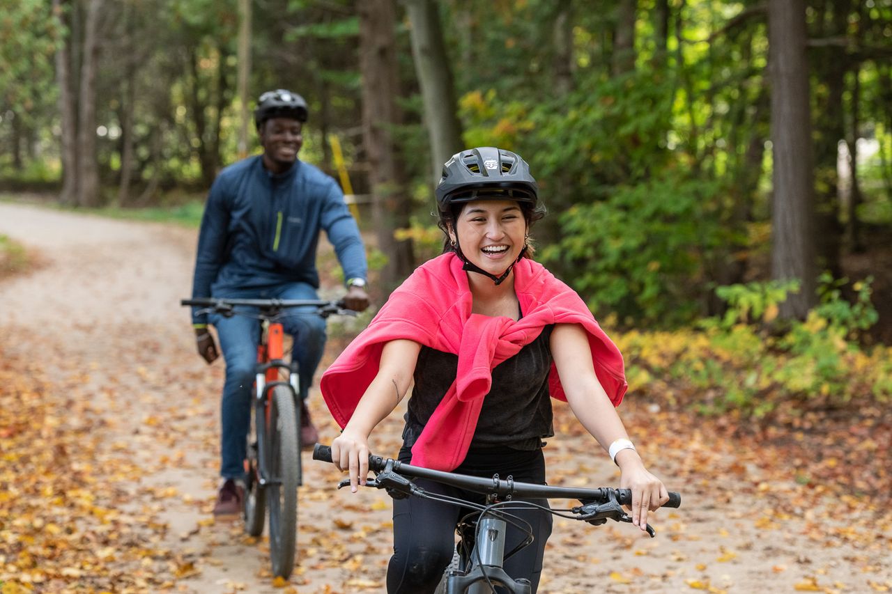 An interractial couple biking through the fall forest at Blue Mountain Resort's Explore Park