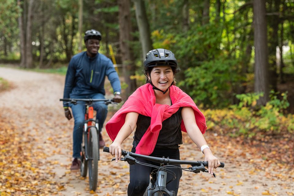 An interractial couple biking through the fall forest at Blue Mountain Resort's Explore Park