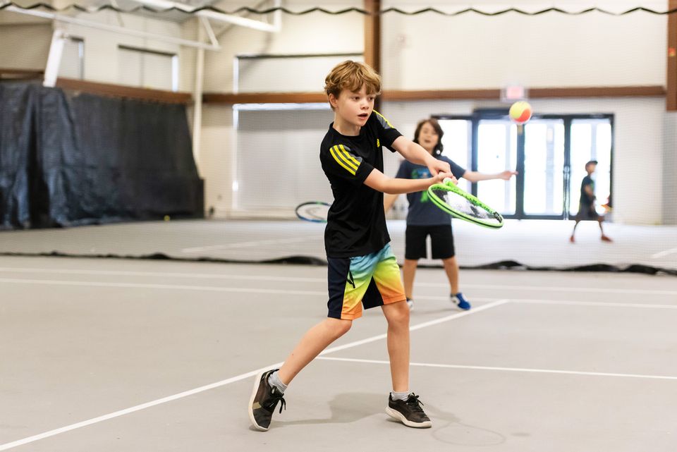 A group of kids playing tennis on the indoor courts at Blue Mountain Resort.