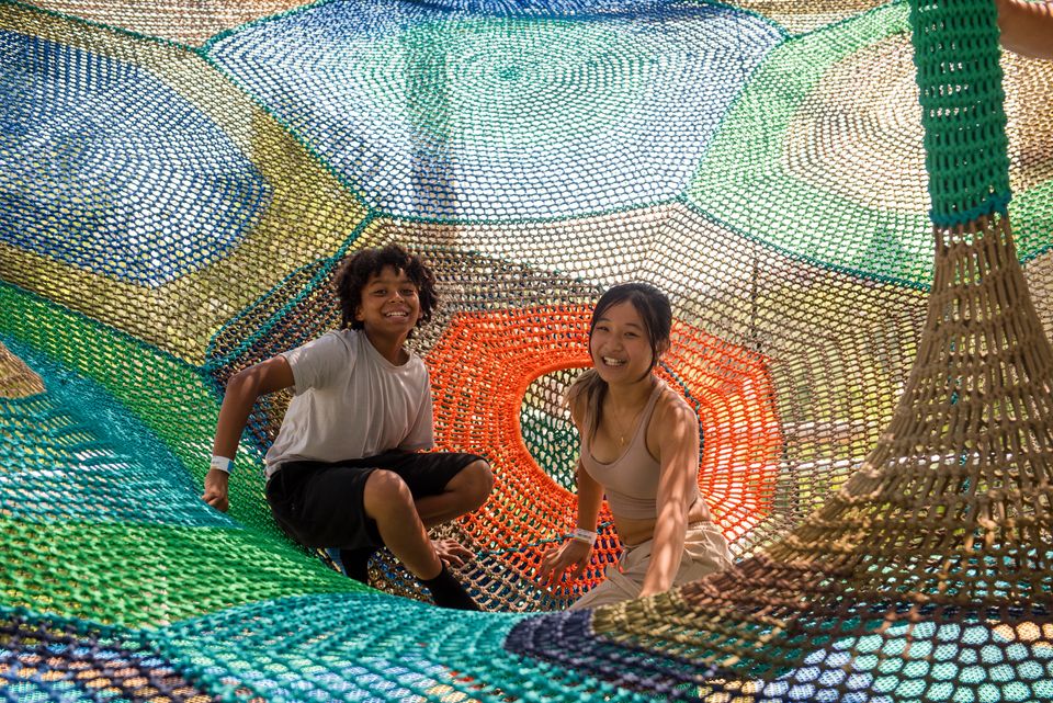 Two kids crawling through the multi-colour netted tunnels at the Cocoon Crawl Net Adventure at Blue Mountain Resort.