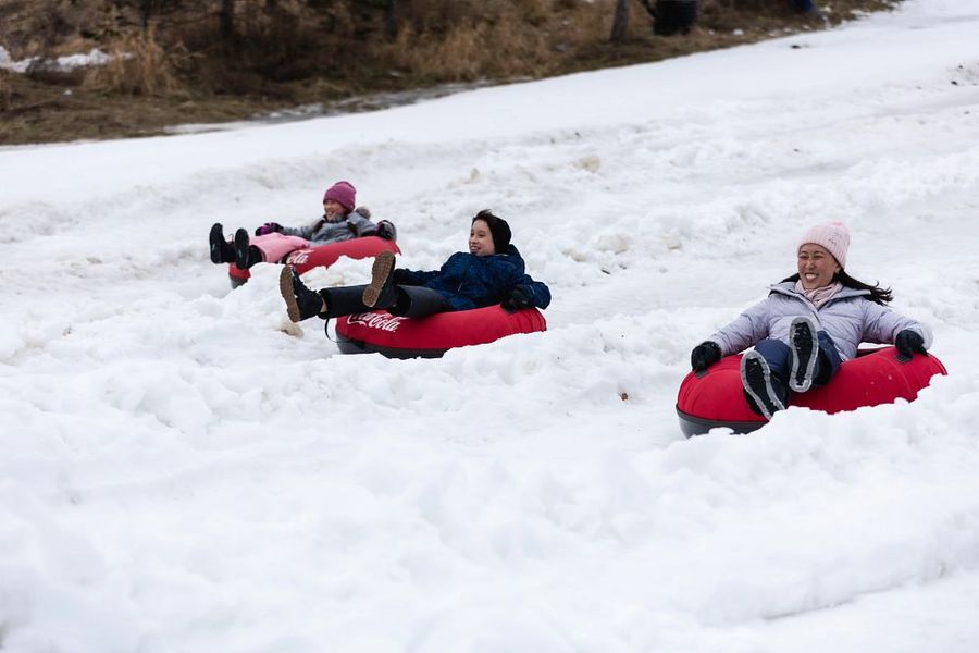 Mom and her two kids speed downhill at the Hike N' Tube Snow Tube Park