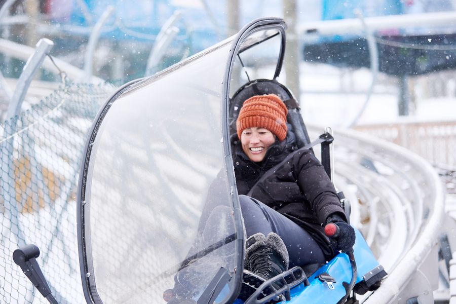 Woman speeding down the Ridge Runner Mountain Coaster for a Winter thrill ride.