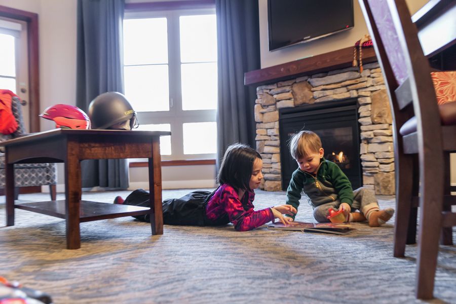 Two toddlers playing on the floor together inside their cozy Village Boutique Suite.