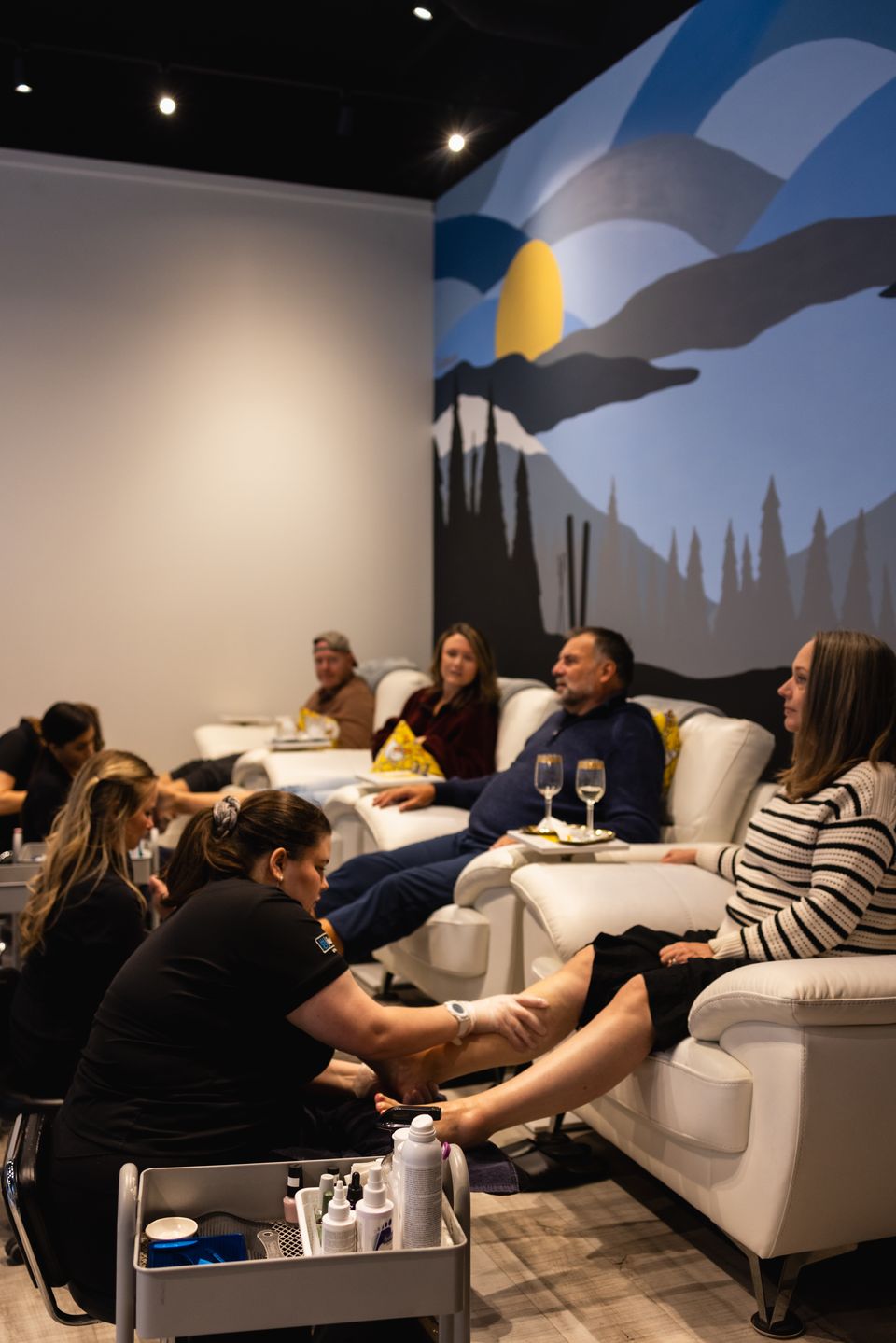 Two couples sitting in the large lounge chairs, getting pampered with pedicures at Beauty Bar by iwa, located in Blue Mountain Village