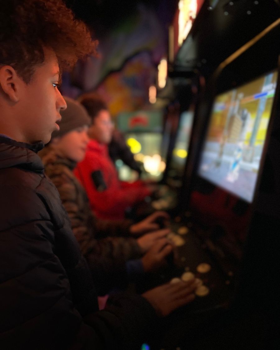 Group of boys lineup beside each other, each playing a different Retro arcade console at The Bunker Arcade.