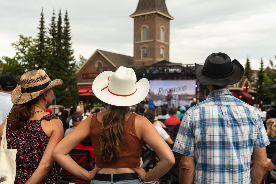 3 country music lovers dressed in their cowboy best enjoying live performances at Country Fest in the Village.