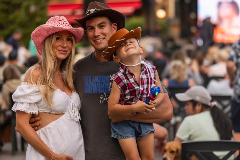 Mom, dad, and their toddler are dressed in full country gear for Gone Country Music Festival in the Village.