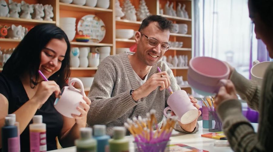 Man and his friends painting their own pottery at Crock-a-Doodle studio.