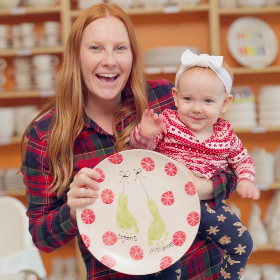Mom and baby visit Crock-a-Doodle to paint a custom Christmas plate using prints of the baby's feet.