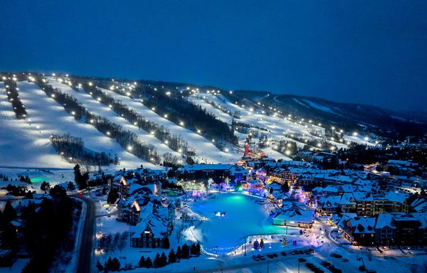 A nighttime aerial view of Blue Mountain and Village, showcasing the lit up slopes and Holiday Magic Light Trail.