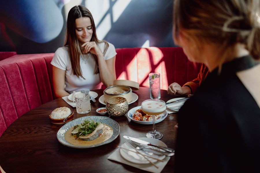 Friends dining at a booth in Mother Tongue restaurant. 
