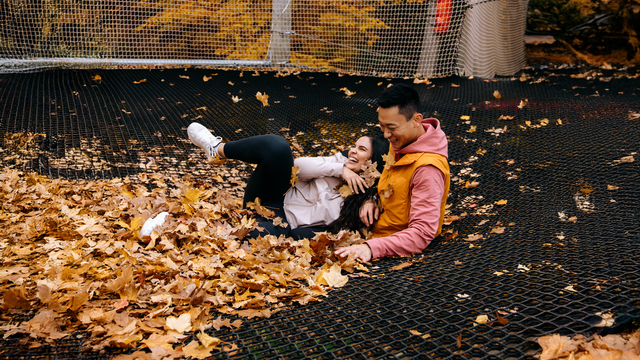 A young couple laughing and embracing on the Canopy Climb Net Adventure among the fall leaves.