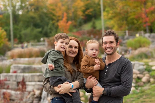 A young family of four posing for a photo at the base of the mountain. 