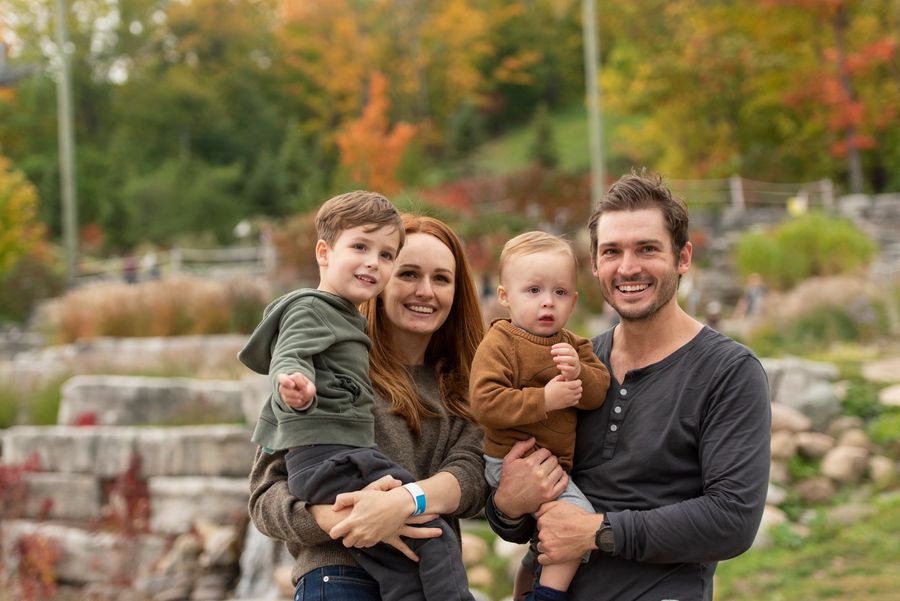 A young family of four posing for a photo at the base of the mountain. 